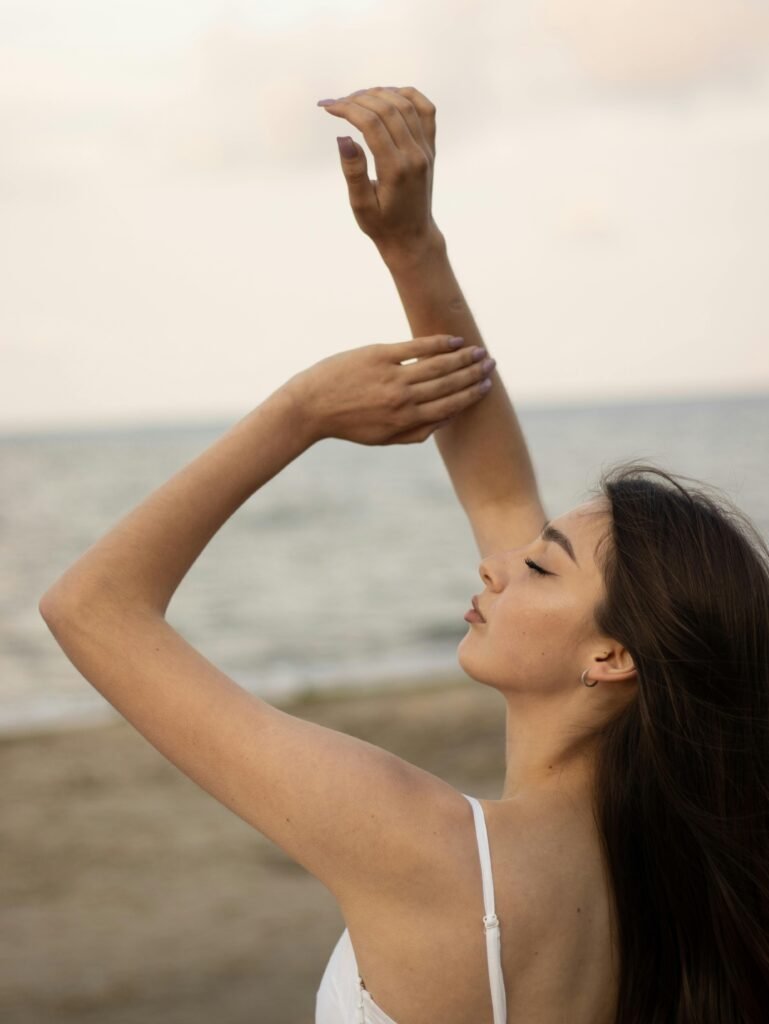 Profile of a woman gracefully posing on a serene beach.